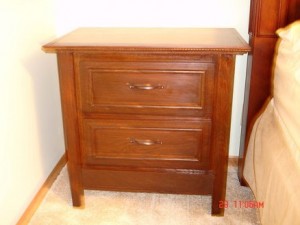 Bedside table with hidden compartment drawer behind bottom panel